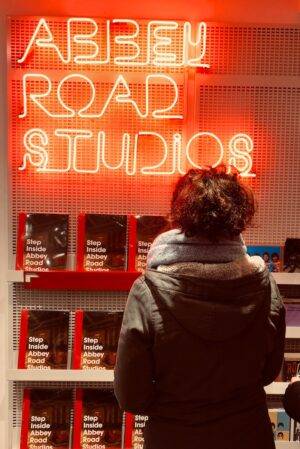 woman in gray scarf standing in front of red and white love neon signage