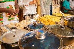 a group of people standing around a table full of food