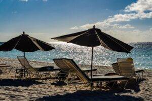 a couple of lawn chairs sitting on top of a sandy beach