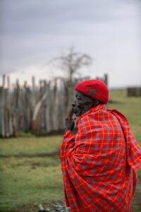 man in red and black plaid dress shirt and black knit cap standing on green grass