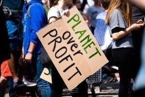 woman holding Planet over Profit placard