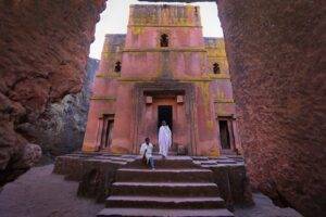 person in white dress in front of pink building