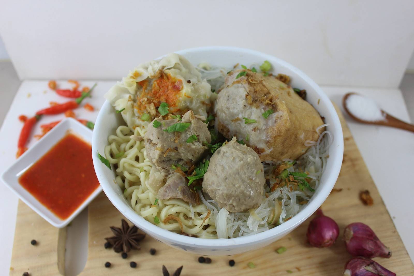 a white bowl filled with meatballs and noodles