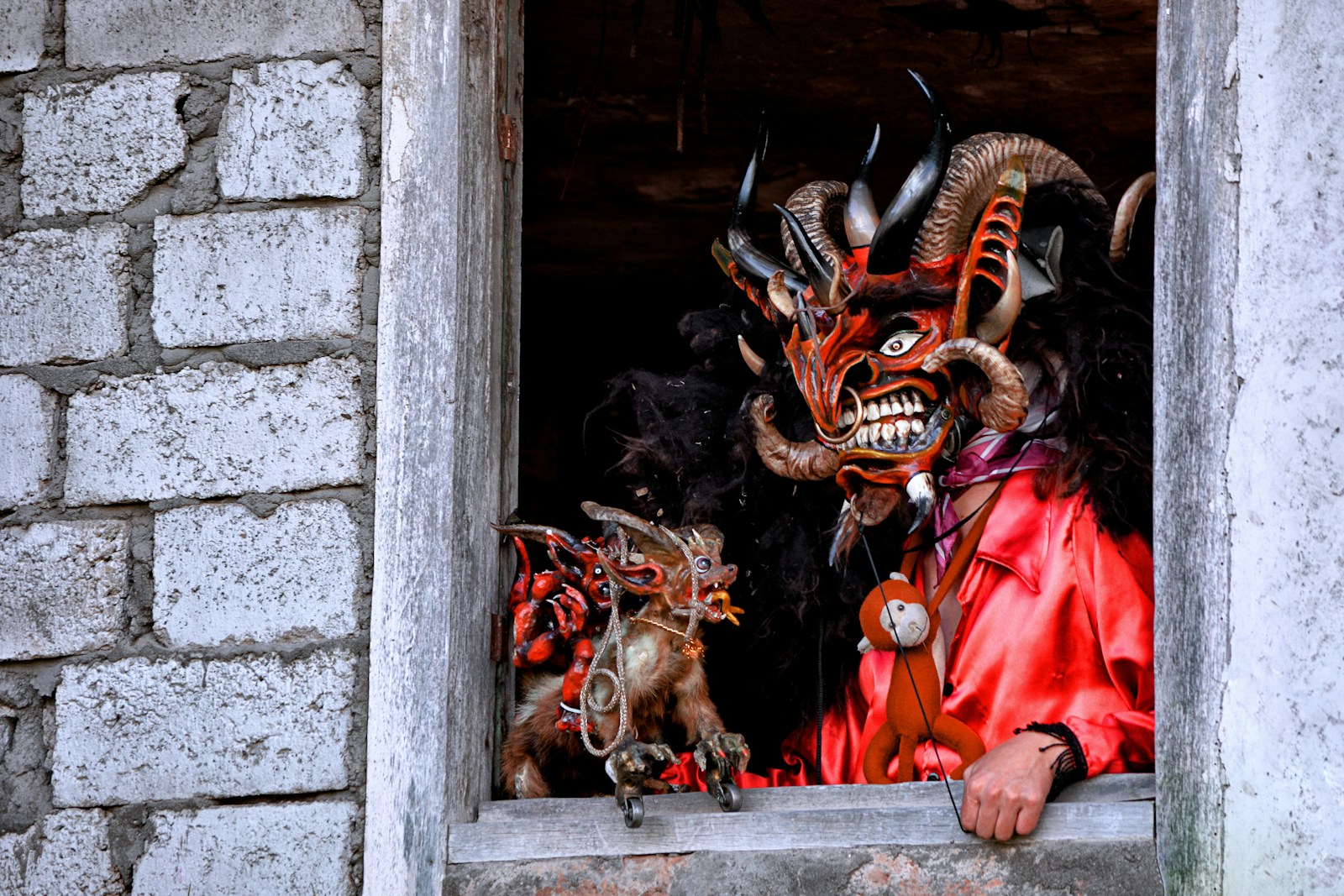 a man in a window with a demon mask on